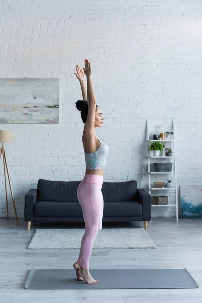 Vue latérale de la femme en tenue de sport debout dans la pose de montagne avec les mains levées — Photo de stock