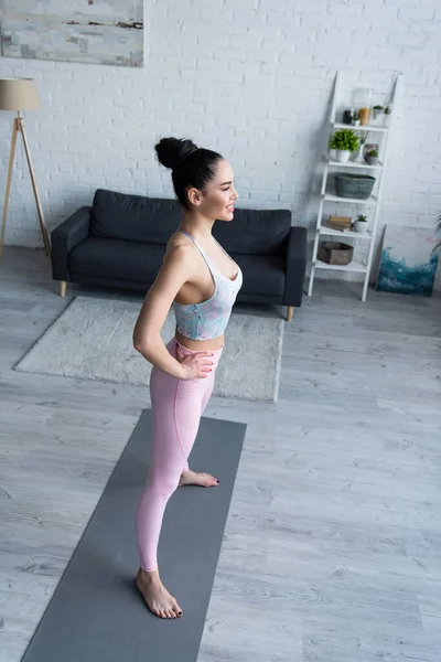 Vue grand angle de la femme pieds nus heureux debout dans la pose d'étoile avec les mains sur les hanches — Photo de stock