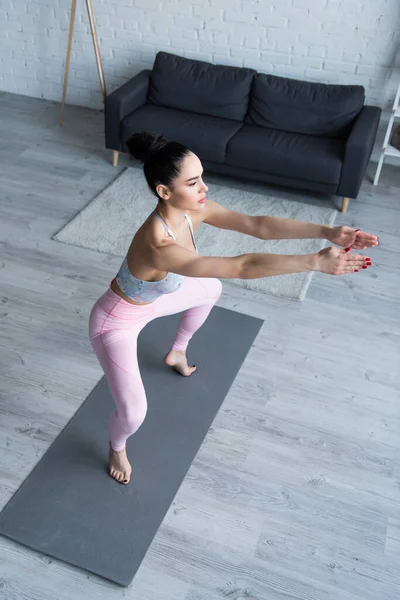 High angle view of barefoot woman in awkward pose on yoga mat — Stock Photo