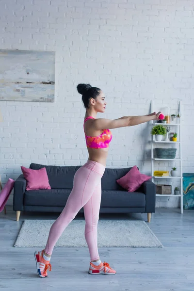 Side view of young woman in sportswear training with dumbbells — Stock Photo