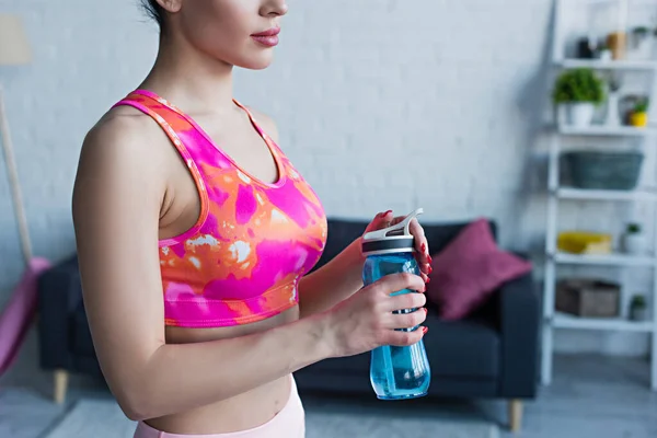 Cropped view of young woman opening sports bottle at home — Stock Photo