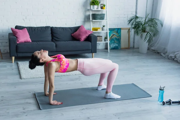 Brünette Frau in Sportbekleidung, die in Reverse-Table-Pose auf Fitnessmatte trainiert — Stockfoto