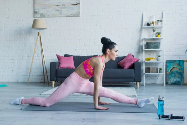 Side view of sportswoman training in front splits pose at home — Stock Photo