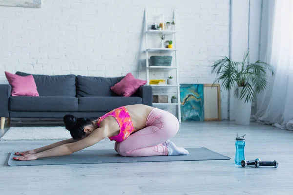 Brunette femme travaillant dans l'angle lié pose sur tapis de fitness — Photo de stock