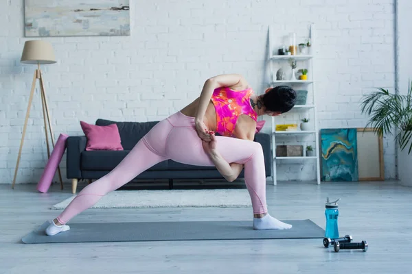 Back view of young woman working out in bound side angle pose at home — Stock Photo