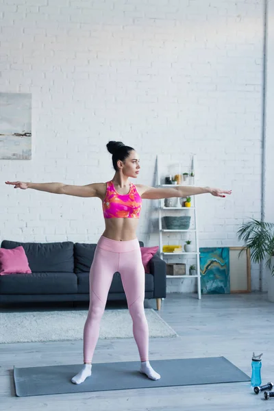 Sportive woman standing in five pointed star pose on fitness mat at home — Stock Photo