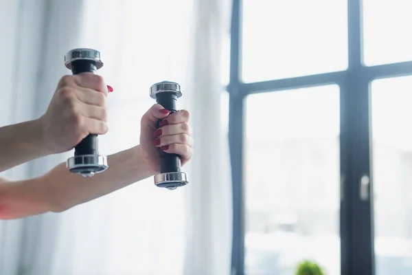 Cropped view of woman exercising with dumbbells at home — Stock Photo
