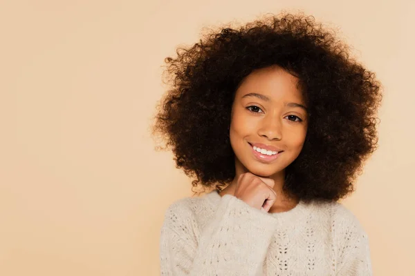 Retrato de niña afroamericana preadolescente sonriente con la mano cerca de la cara aislada en beige - foto de stock
