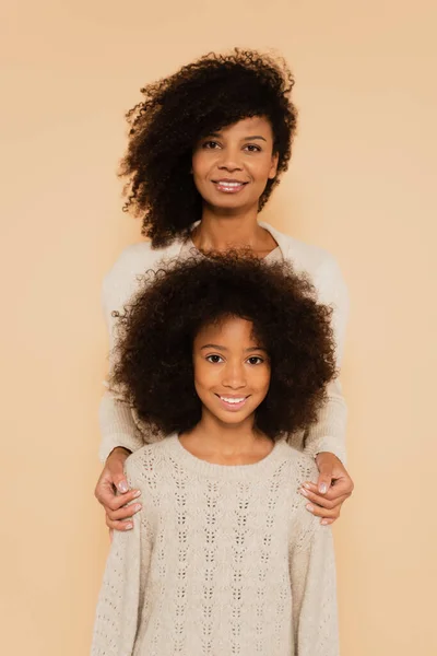 Portrait of happy african american preteen daughter with mother isolated on beige — Stock Photo