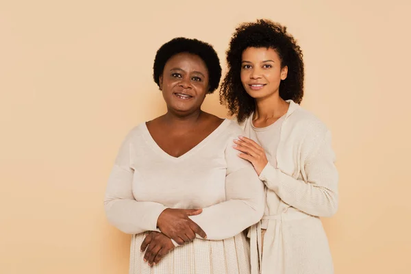 Cheerful african american middle aged grandmother and adult daughter female standing together on beige background — Stock Photo