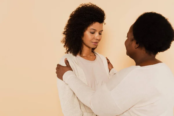 African american middle aged mother supporting sad adult daughter with hands on shoulders isolated on beige — Stock Photo