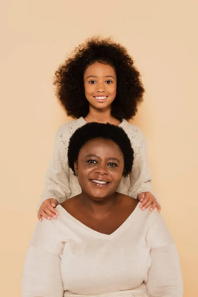 Cheerful african american granddaughter with grandmother isolated on beige — Stock Photo