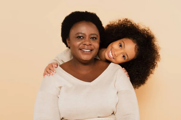 Joyful african american granddaughter with grandmother isolated on beige — Stock Photo