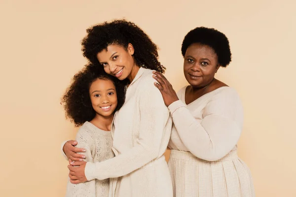 Afro americano nonna abbracciare con sorridente figlia e nipote isolato su beige — Foto stock