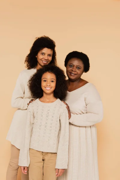 Lächelnde Familie aus afrikanisch-amerikanischer Mutter, Großmutter und Enkelin isoliert auf beige — Stockfoto