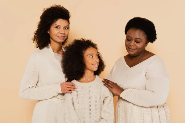 African american mother and grandmother standing with smiling granddaughter isolated on beige — Stock Photo