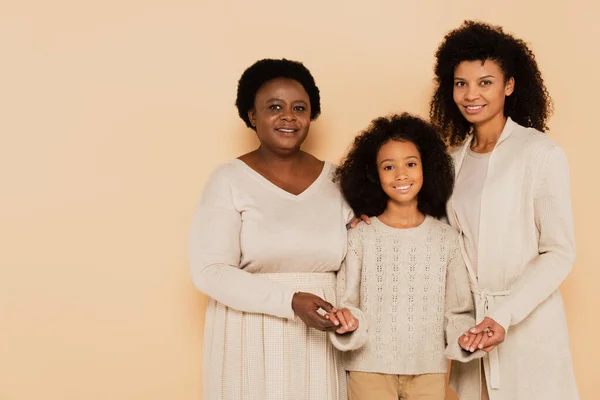 African american grandmother and daughter holding hands with granddaughter on beige background — Stock Photo