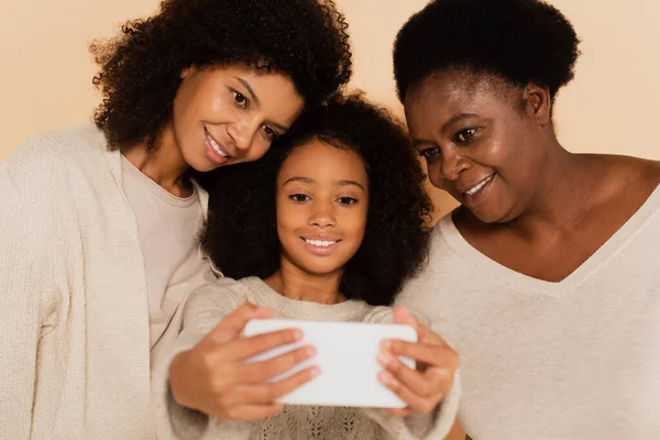 Afro-américaine fille, petite-fille et grand-mère prendre selfie sur téléphone portable ensemble sur fond beige — Photo de stock