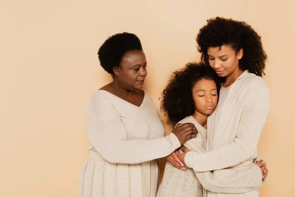 Afrikanisch-amerikanische Mutter und Großmutter umarmen und unterstützen traurige Enkelin auf beigem Hintergrund — Stockfoto