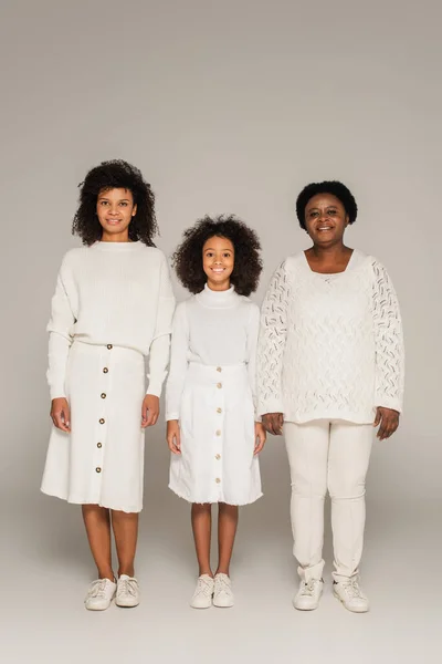 Happy african american mother, daughter and grandmother in white clothes on grey background — Stock Photo