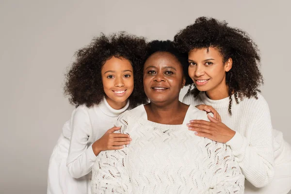 Portrait de fille afro-américaine et mère embrassant grand-mère et regardant la caméra isolée sur gris — Photo de stock