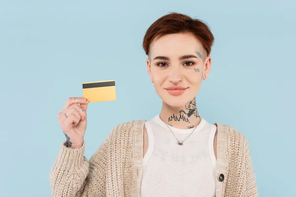 Donna allegra e tatuata con carta di credito isolata sul blu — Foto stock