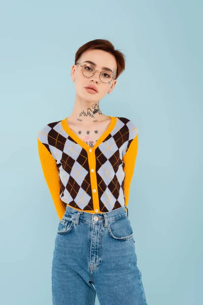 Junge tätowierte Frau mit Brille posiert isoliert auf blauem Grund — Stockfoto
