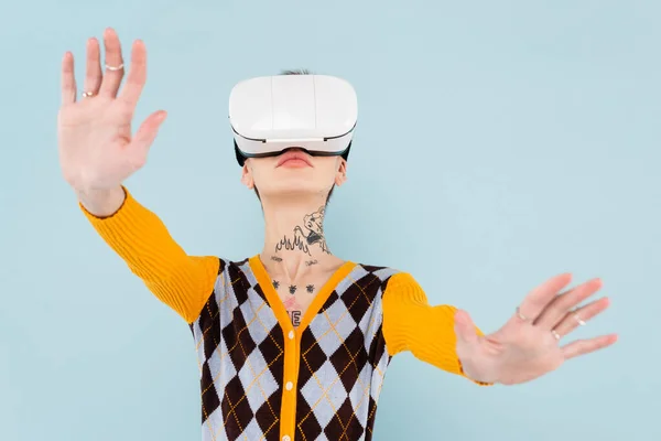 Tattooed young woman in vr headset gesturing isolated on blue — Stock Photo