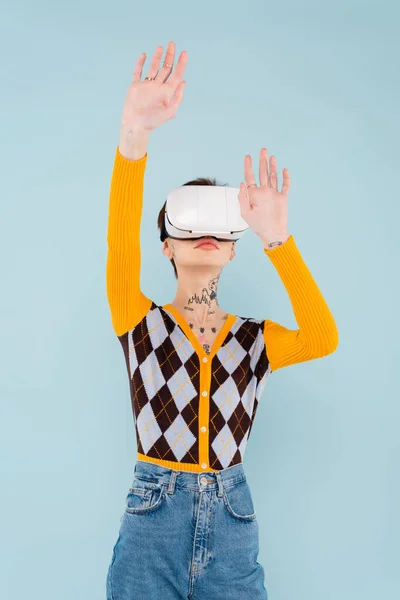 Young tattooed woman in vr headset gesturing isolated on blue — Stock Photo