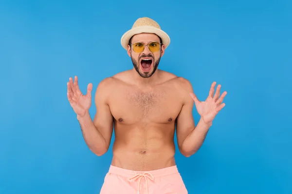 Homem irritado em óculos de sol e chapéu de sol gritando isolado em azul — Fotografia de Stock