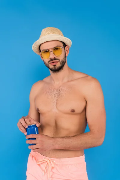 Hombre sin camisa en gafas de sol sosteniendo bebida enlatada aislada en azul - foto de stock