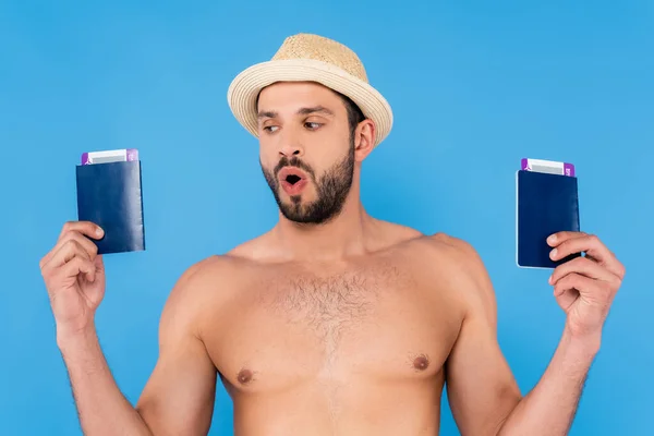 Emocionado hombre sin camisa con sombrero de paja sosteniendo pasaportes y tarjetas de embarque aislados en azul - foto de stock