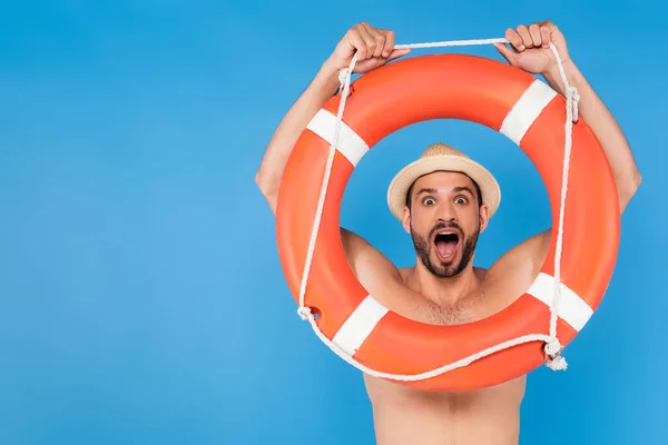 Homme torse nu excité en chapeau de soleil tenant la bouée de vie isolée sur bleu — Photo de stock