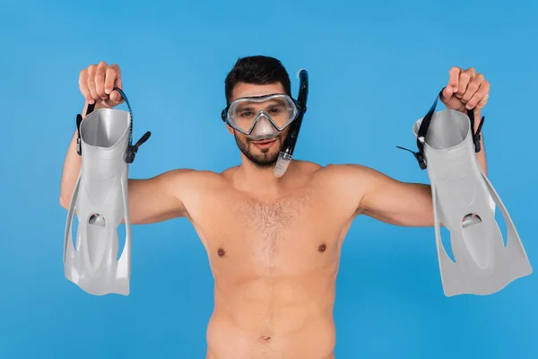 Shirtless man in swimming goggles holding flippers isolated on blue — Stock Photo