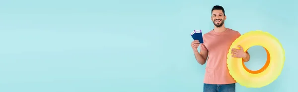 Homem positivo com passaportes e anéis infláveis isolados em azul, bandeira — Fotografia de Stock