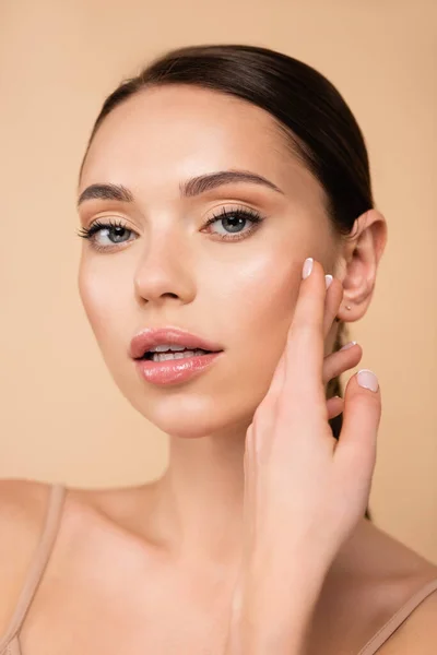 Jolie femme avec maquillage naturel regardant caméra isolée sur beige — Photo de stock