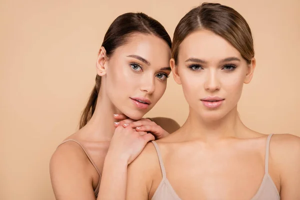 Sensual woman leaning of shoulder of friend isolated on beige — Stock Photo