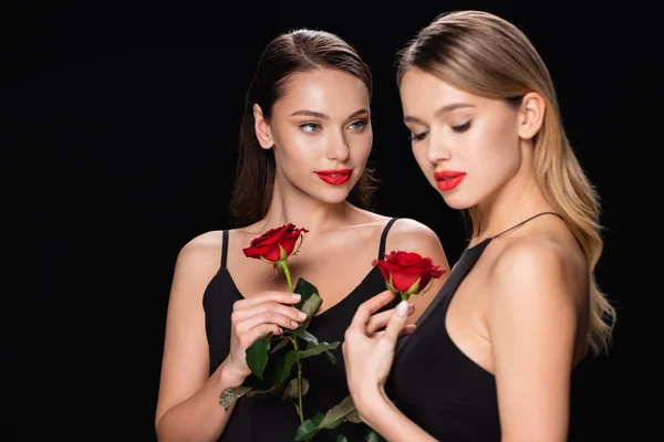 Красивые, молодые женщины позируют с красными розами изолированы на черном — стоковое фото