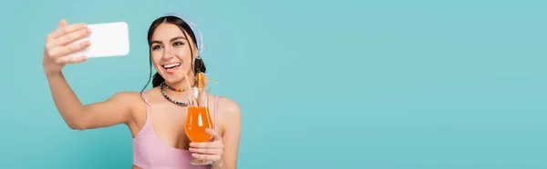 Lächelnde Frau hält Cocktail in der Hand und macht Selfie mit Smartphone auf blauem Banner — Stockfoto