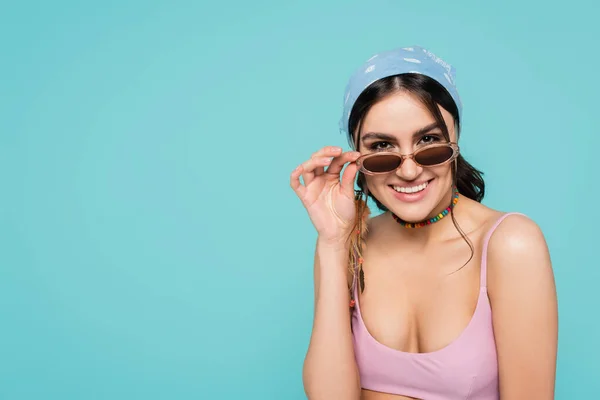 Jeune femme en lunettes de soleil souriant à la caméra isolée sur bleu — Photo de stock