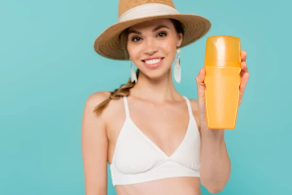 Sunscreen in hand of blurred woman isolated on blue — Stock Photo