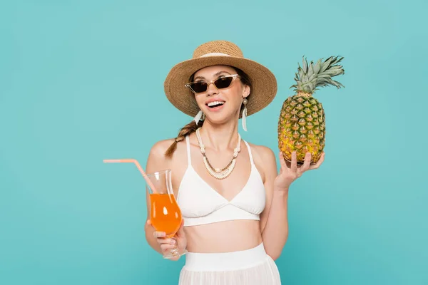 Fröhliche Frau mit Sonnenbrille mit Ananas und Cocktail auf blauem Grund — Stockfoto