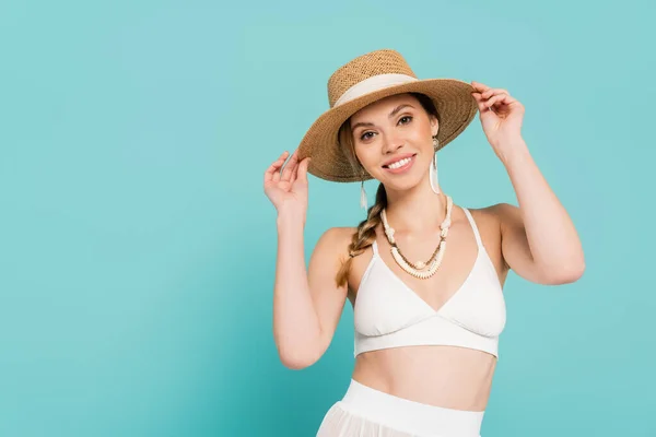 Cheerful woman in straw hat looking at camera isolated on blue — Stock Photo