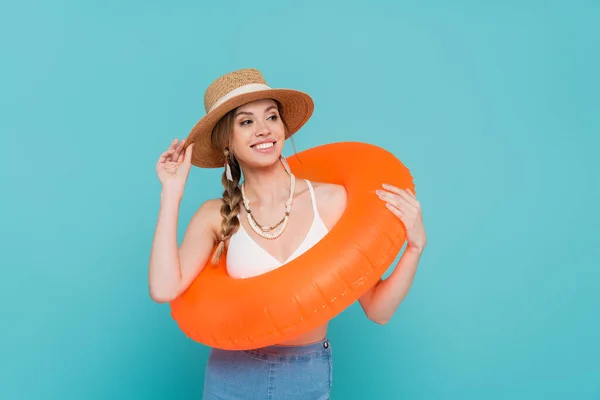 Smiling woman in straw hat holding swim ring isolated on blue — Stock Photo