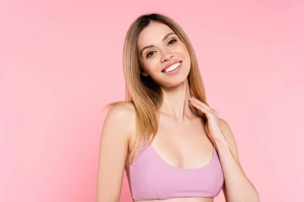 Mujer sonriente en la parte superior del traje de baño mirando a la cámara aislada en rosa - foto de stock