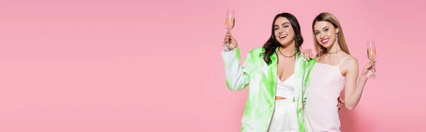 Pretty women holding glasses of champagne on pink background, banner — Stock Photo