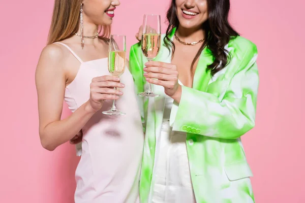 Cropped view of young women with champagne on pink background — Stock Photo