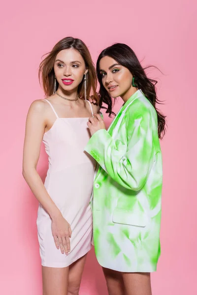 Mujer con chaqueta abrazando sonriente amigo sobre fondo rosa — Stock Photo