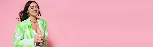 Mulher sorridente no casaco segurando vidro com champanhe no fundo rosa, banner — Fotografia de Stock
