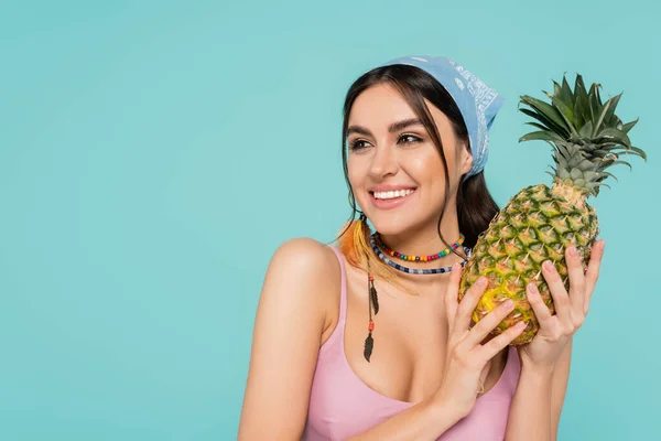 Mulher sorridente em bandana segurando abacaxi isolado em azul — Fotografia de Stock